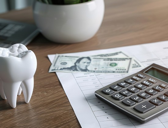 Large model tooth next to money and calculator on desk