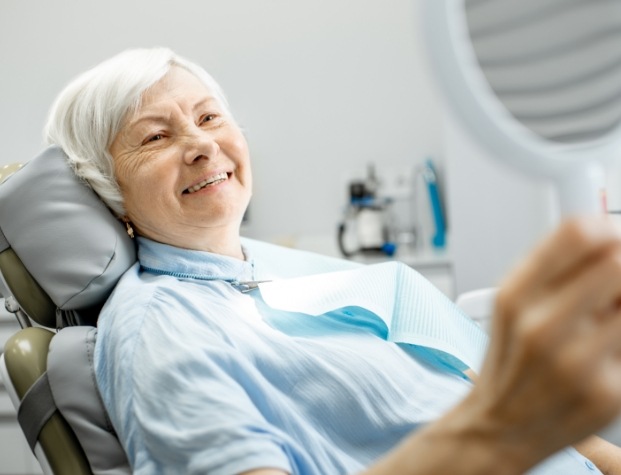 Senior dental patient looking at her smile in mirror