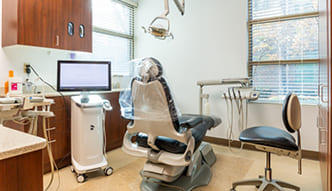 Young man in dental chair looking at his smile in yellow mirror