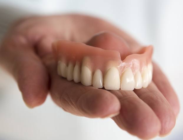 Hand holding a full denture