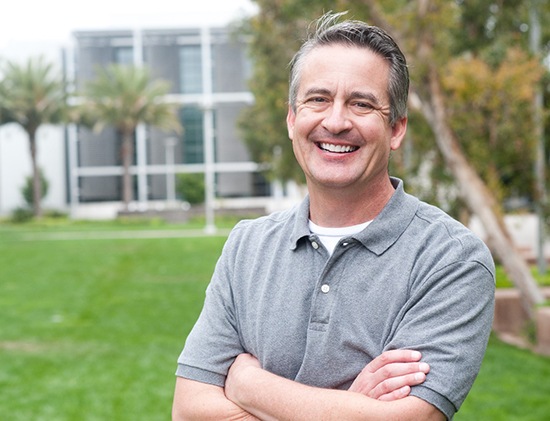 man smiling while outside with arms crossed