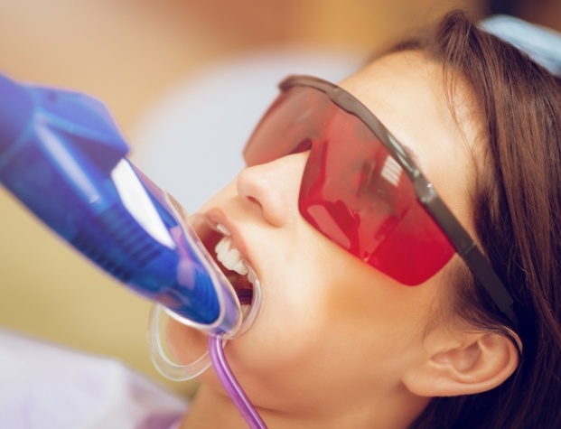 Young woman with fluoride treatment trays over her teeth in dental chair