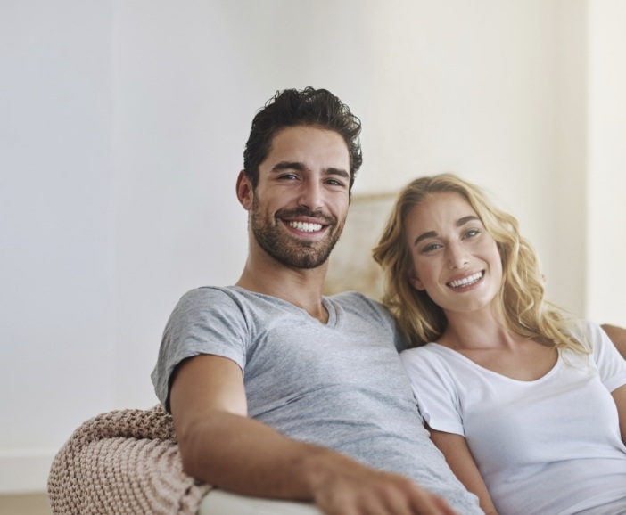 Smiling man and woman sitting on couch together