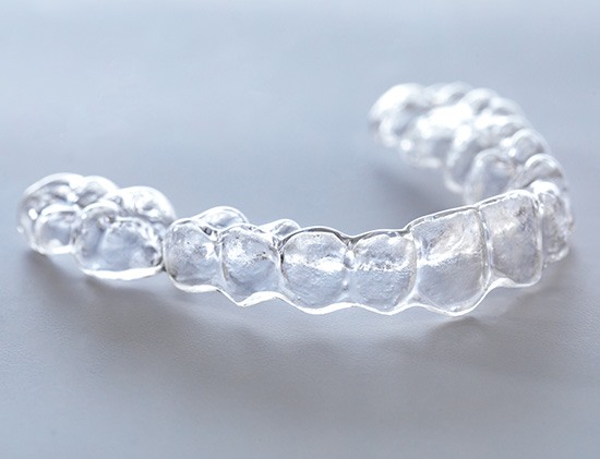 Smiling patient holding clear aligner