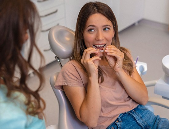 Woman smiling while holding clear aligners