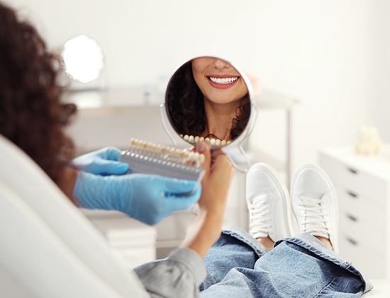 Smiling woman looking at shade scale in mirror