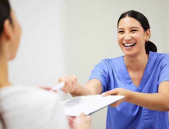 Dental assistant smiling while handing patient form