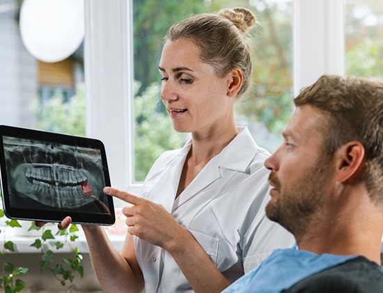 Dental assistant going over X-ray with patient 