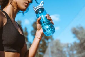 Woman standing outside, drinking from water bottle