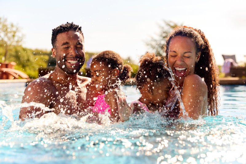 Family with good dental health smiling in the pool