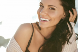 Woman smiling with brilliant teeth and backlit by sunlight